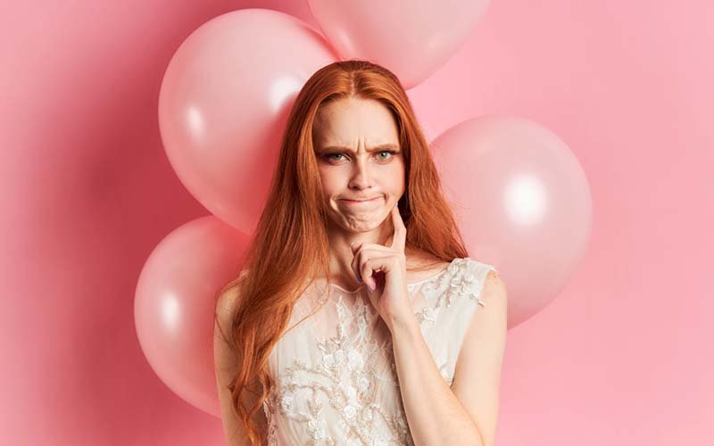 23-serious-upset-woman-with-auburn-hair-wearing-white-dress-pink-air-ballons-behind-her.jpg