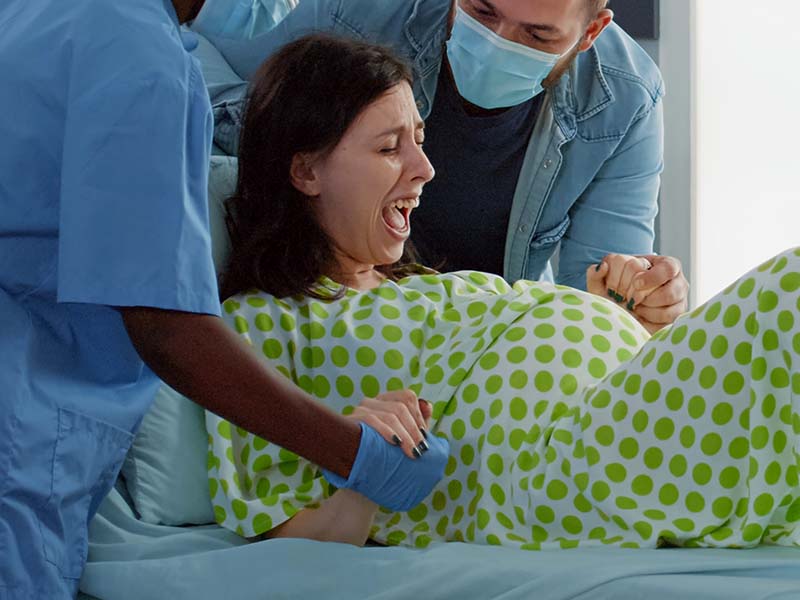 4-DCStudio-pregnant-woman-giving-birth-hospital-ward-bed-with-obstetrics-doctor-african-american-nurse-giving-medical-assistance-support-young-man-sitting-with-wife-childbirth.jpg